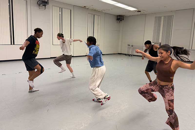 Five students rehearsing in a dance studio