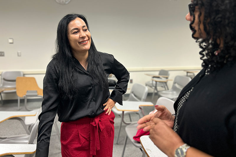 A woman stands talking to another woman