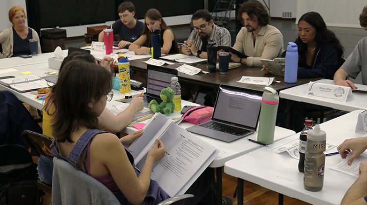 Group of people sitting around a table reading a play