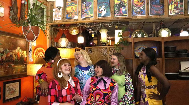 Group of laughing young women dressed in 1960s fashion