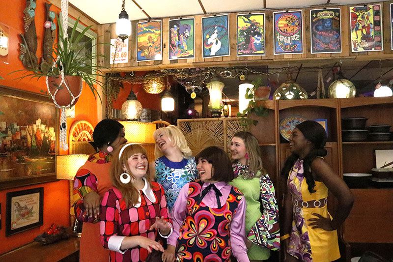 Group of laughing young women dressed in 1960s fashion
