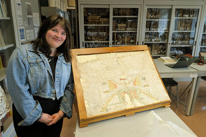 Young woman standing next to archived document