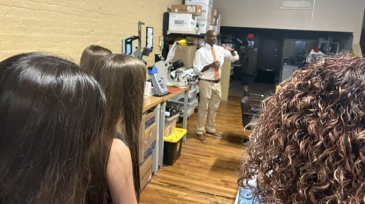 Man standing in shop speaking to a group of students