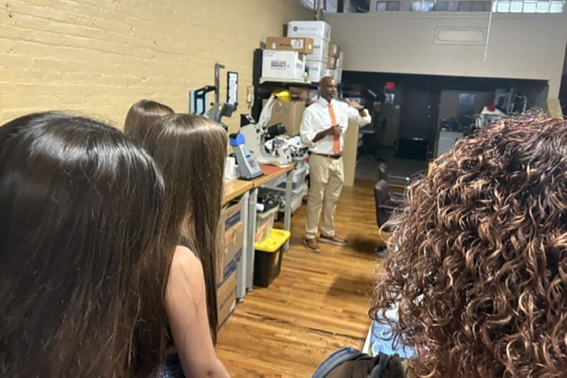 Man standing in shop speaking to a group of students