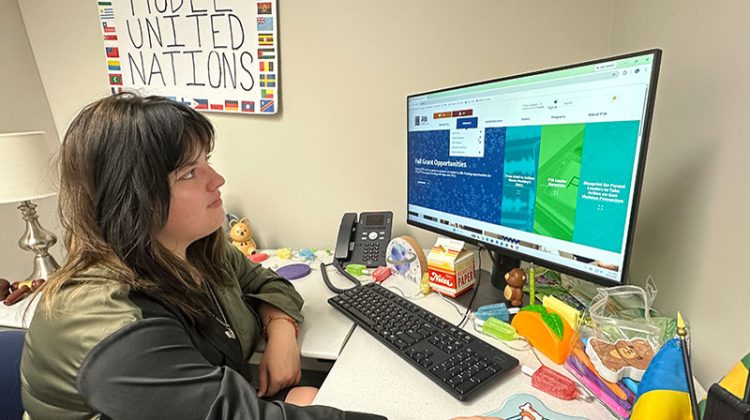 Young woman works at desk on computer