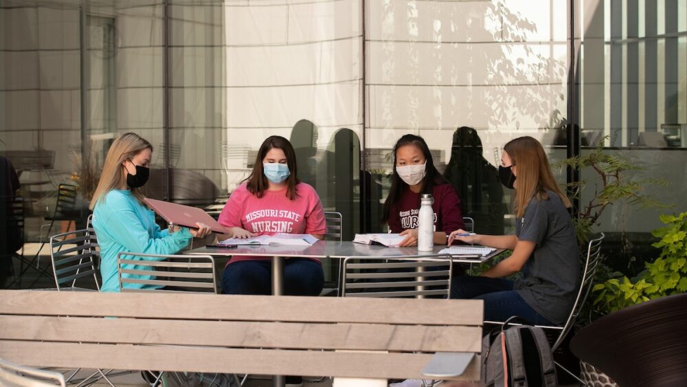 Four Missouri State nursing students wear protective face coverings and work together on a project.