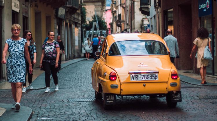 Car driving down cobble stone street in Italy.