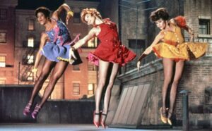 Three Woman leaping in brightly colored attire on a rooftop