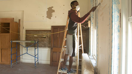 student scrapes paint in Fairbanks building