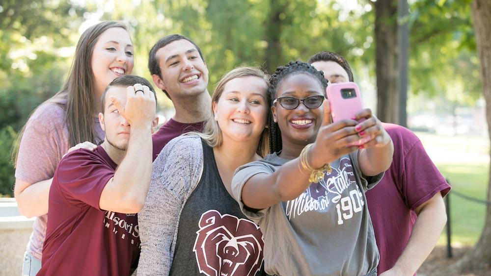 Students dressed in Missouri State shirts taking a selfie with a pink phone