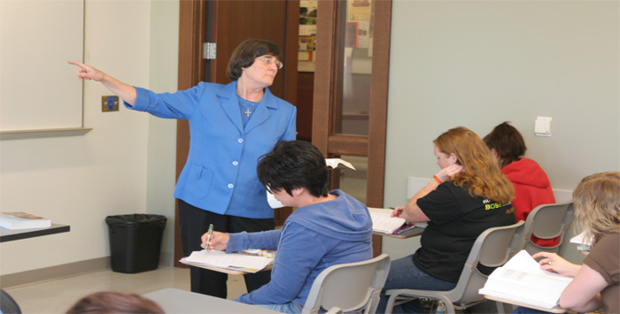 Dr. Pauline Nugent points to the whiteboard in class